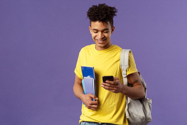 back school university concept portrait pleased good looking male student texting friend looking mobile phone his way classes campus hold notebooks backpack 1258 85571559227826409672299